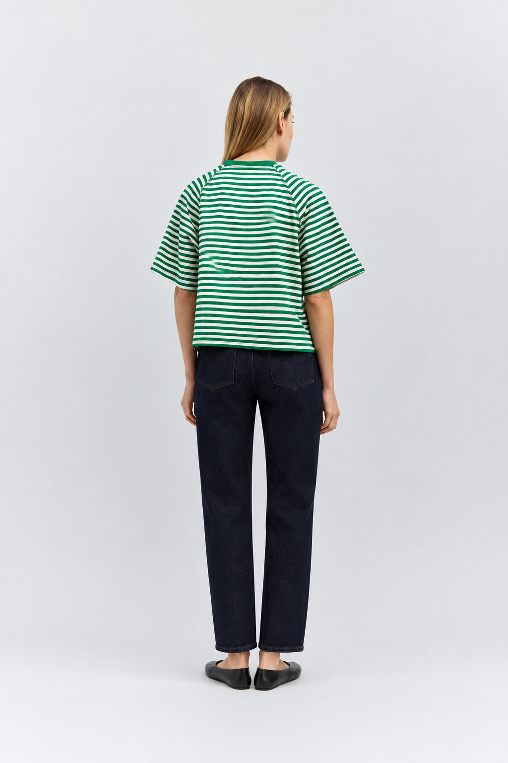 Person wearing a green and white striped shirt and dark jeans on a white background