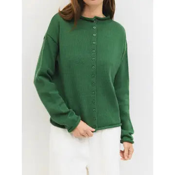 A woman wearing a green ribbed knit long-sleeve button-up sweater and white pants, shown from the neck down against a plain light background.
