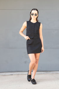 Woman wearing a black sleeveless top and skirt with sunglasses.