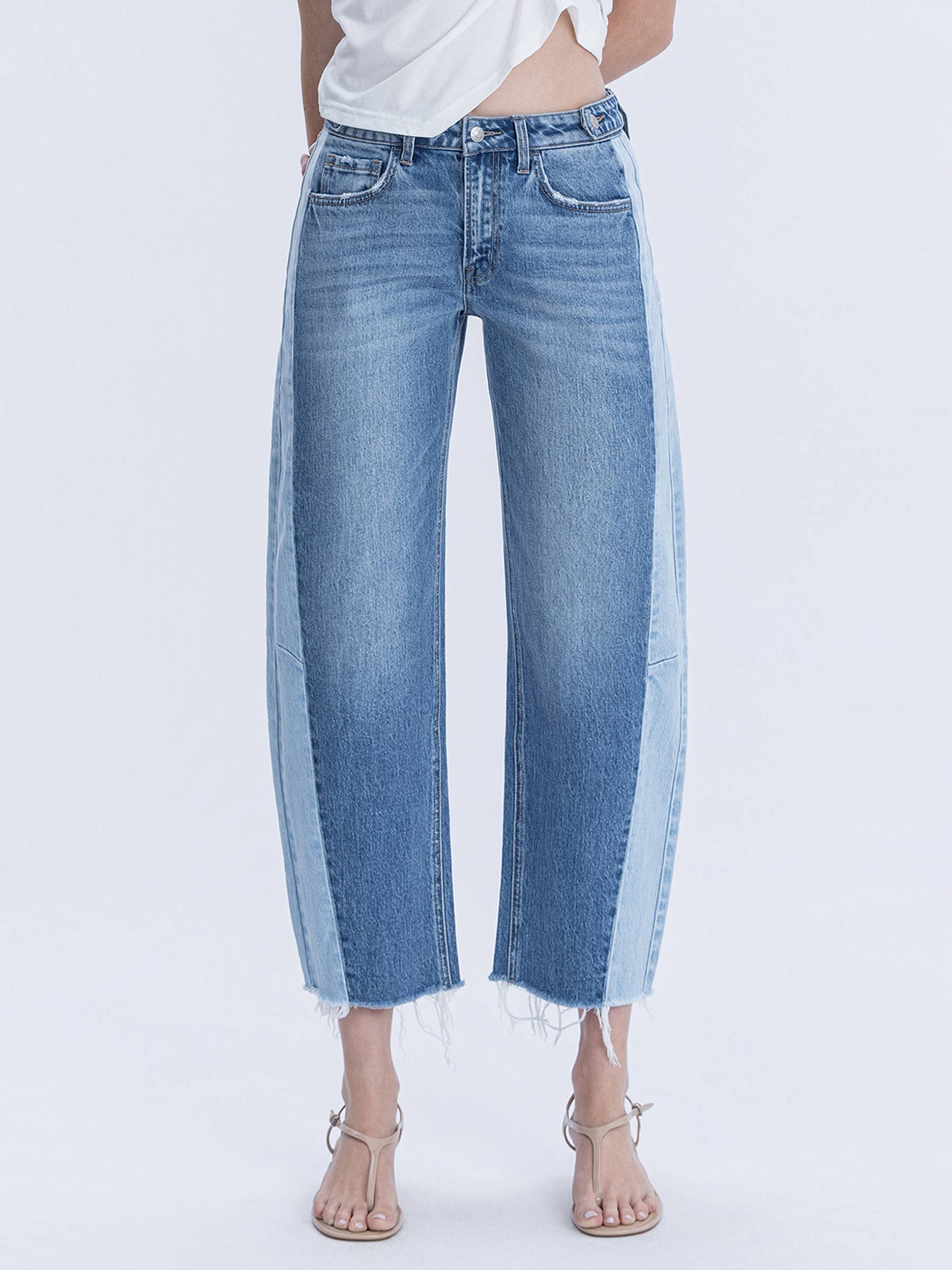 Woman wearing high waisted two tone barrel raw hem denim jeans