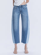 Woman wearing high waisted two tone barrel raw hem denim jeans