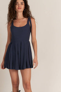 Navy blue pleated skirt romper with hidden shorts, tie shoulder detail